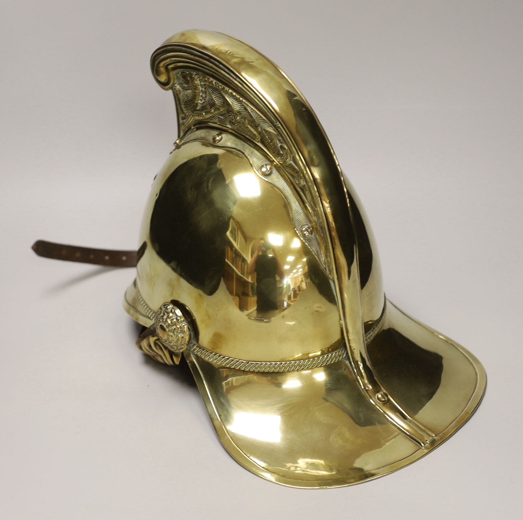 A late 19th/early 20th century brass Merryweather fire brigade helmet with embossed decoration and leather liner, 34cm in length